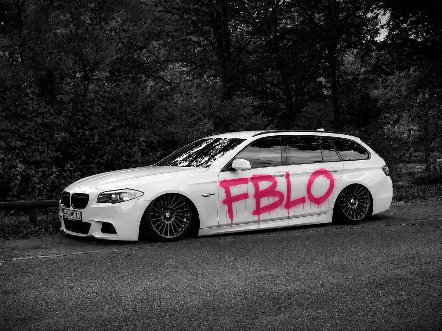 Vit BMW med FBLO-graffiti i skogen